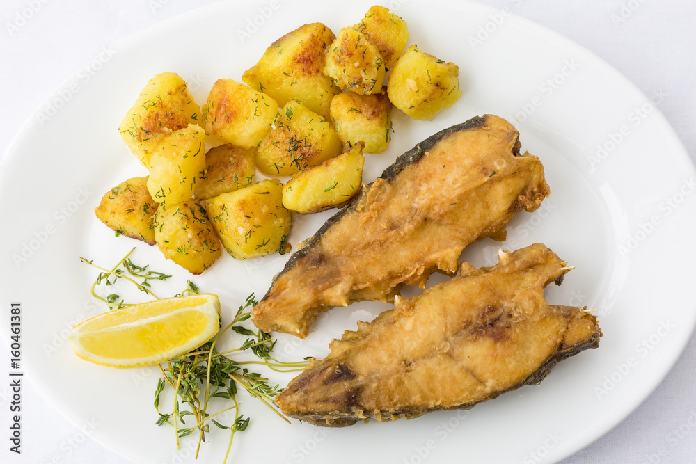 Fried fish garnished with potatoes, close up, top view at restaurant Fried fish garnished with potatoes, close up, top view at restaurant