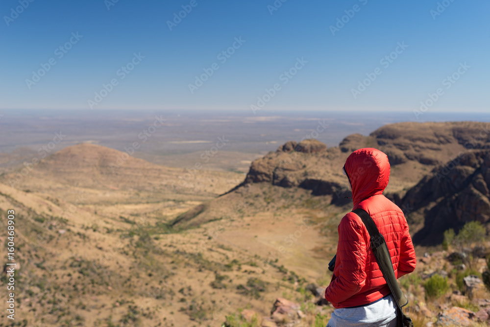 Tourist standing on rock and looking at the panoramic view in Marakele National Park, one of the travel destination in South Africa. Concept of adventure and traveling people.