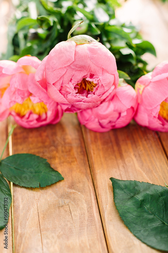 love, wedding, romance, nature, celebration concept - close-up of soft pink peonies with bright yellow core collected in gorgeous bouquet lying on wooden table