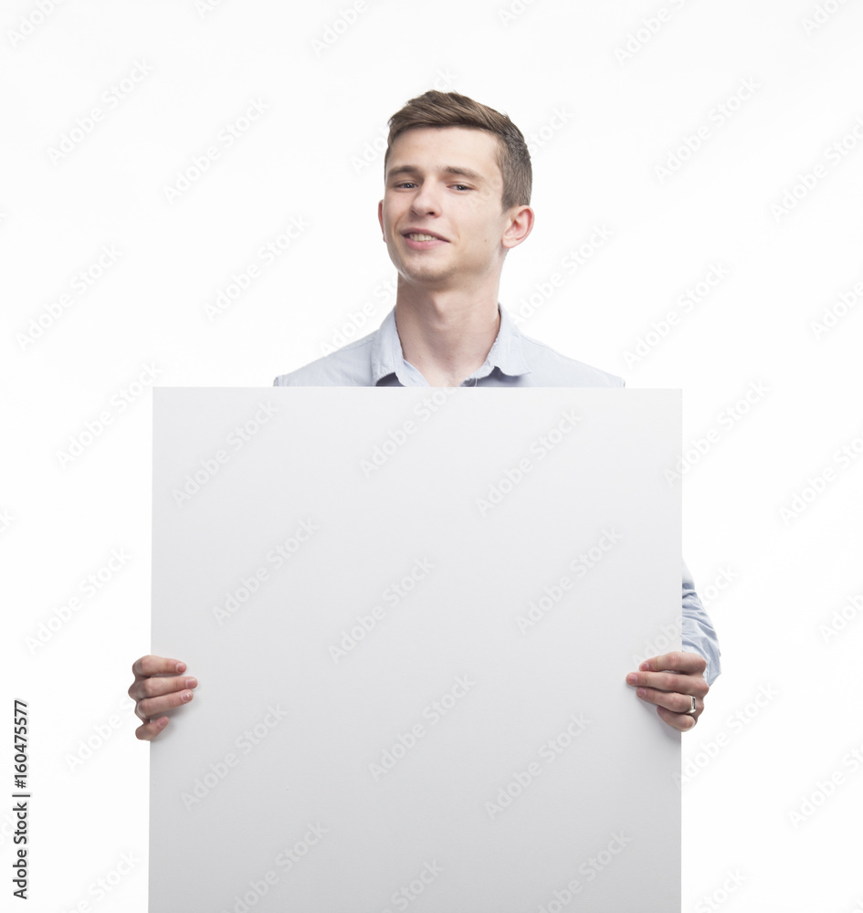 Young happy man showing presentation, pointing on placard over g Young happy man showing presentation, pointing on placard over g