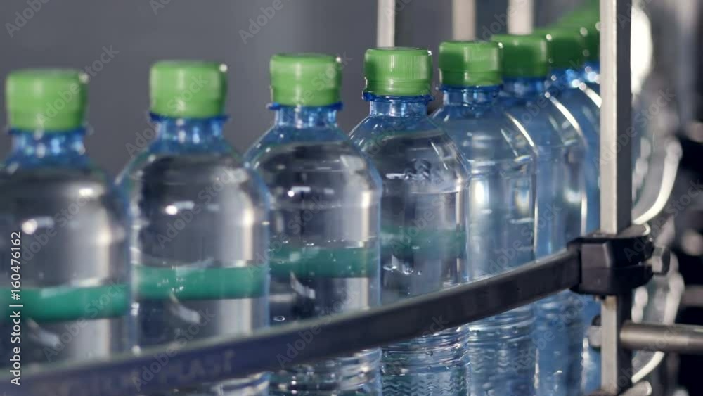 Capped bottles filled with water moving on a conveyor. Capped bottles filled with water moving on a conveyor.