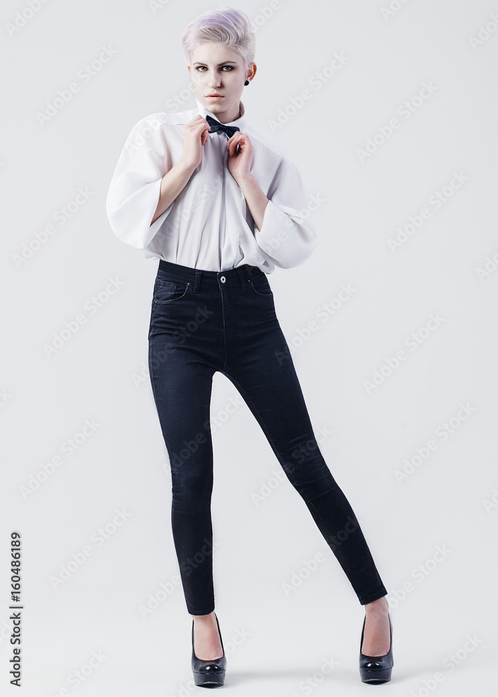 Attractive young female dressed in formal white shirt and black jeans  indicates with thumb away Stock Photo by StudioVK