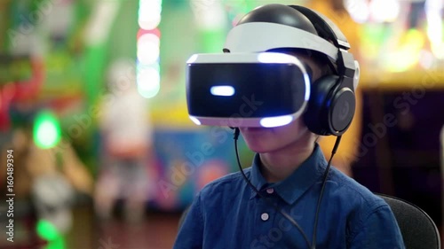 Young boy playing in virtual reality on the console, modern entertainment technology, during school holidays