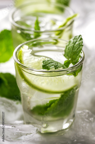 Healthy tasty fresh refreshing detox water in glasses with lime, mint and ice on wooden background. Closeup. Healthy Life Concept.