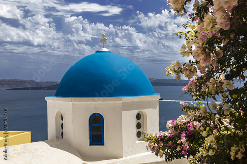 Greek Orthodox Church of St. Nicholas in the background waters of the Aegean sea in Oia town on Santorini island in Greece