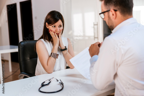 Hispanic doctor talking with patient with test results on paper
