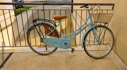 Blue bicycle tied to a railing.