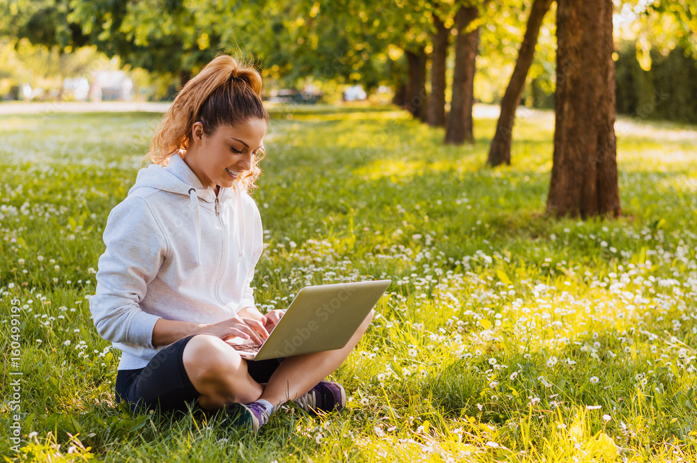 Young woman sitting on the lawn working on her notebook Young woman sitting on the lawn working on her notebook