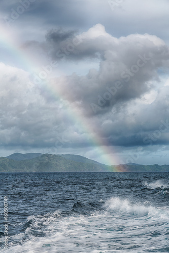the rainbow from ocean and island in background