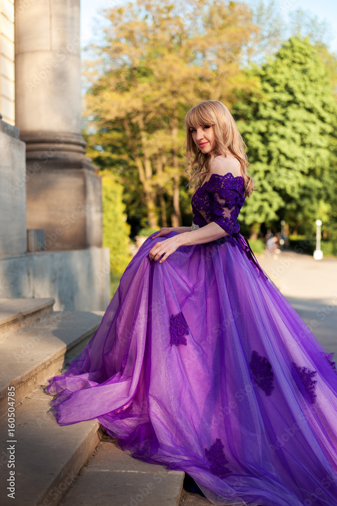 blonde girl in violet dress stending on stairs 