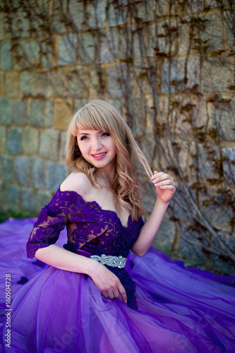 blonde girl in violet dress plays with her hair