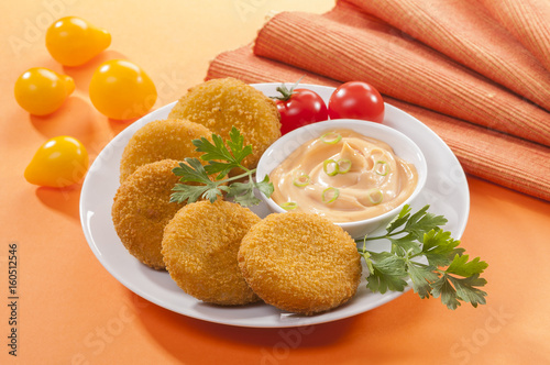 Chicken and cheese fried tikki with lemon and cherry tomato on orange background