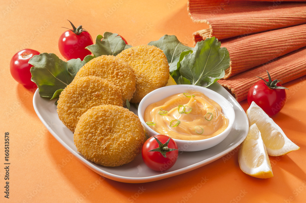 Chicken and cheese fried tikki with lemon and cherry tomato on orange background
