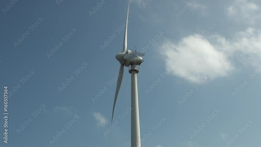 Wind turbines are moving at a wind power plants in Penghu Island, Taiwan. The sky is blue and there are clouds. Wind turbines are moving at a wind power plants in Penghu Island, Taiwan. The sky is blue and there are clouds.