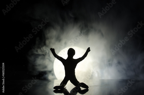 Conceptual image with sandglass and and man with moon at background with fog. Silhouette of toy figure touching hourglass. deadline concept.
