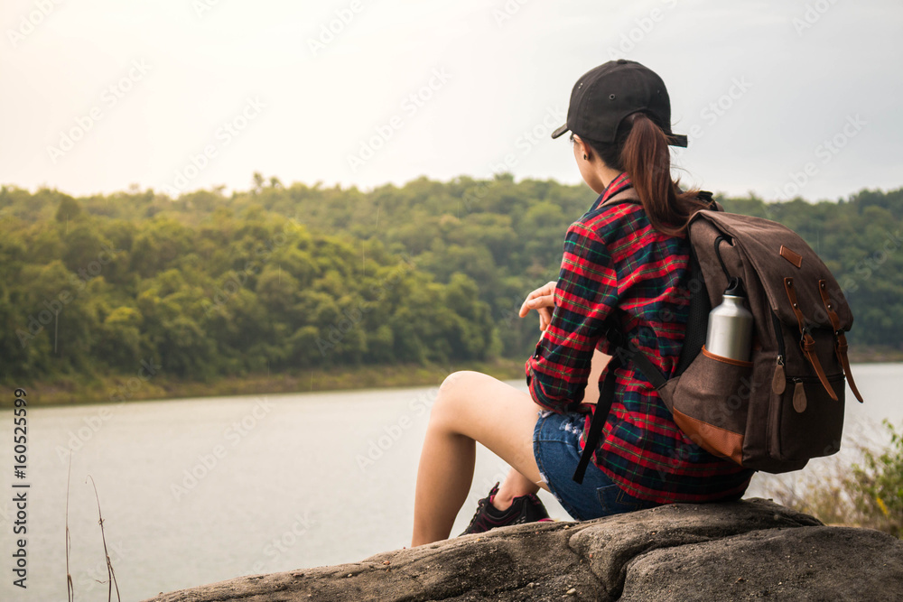 Woman with backpack sit by the the riverside.