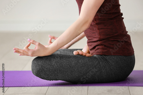 Fototapeta Naklejka Na Ścianę i Meble -  Young woman practicing yoga indoors, close up