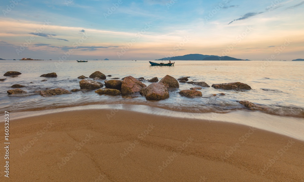 Looking out over the south china sea in Nha Trang bay just after sunset with fishing boats, large rocks and a sandy beach in the foreground. Looking out over the south china sea in Nha Trang bay just after sunset with fishing boats, large rocks and a sandy beach in the foreground.