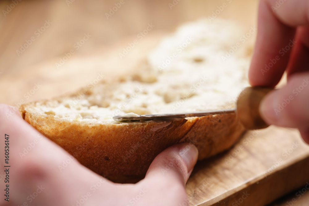 young female hands spreading butter on bread - obrazy, fototapety, plakaty 