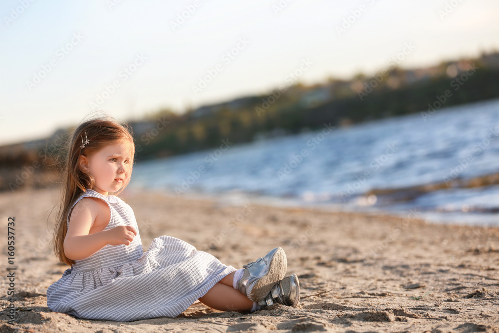 Cute little girl sitting near river