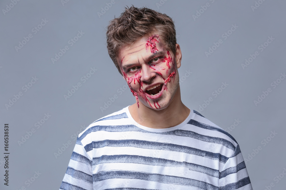 Obraz premium Young man with Halloween makeup on grey background