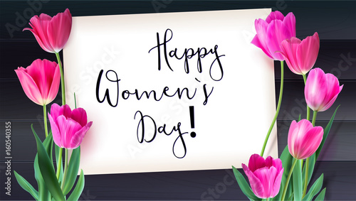 Greeting card with tulips around the sheet of paper with text on background from dark wooden plank. Realistic flowers tulips with petals and leaves, festive composition. Template for your creativity.