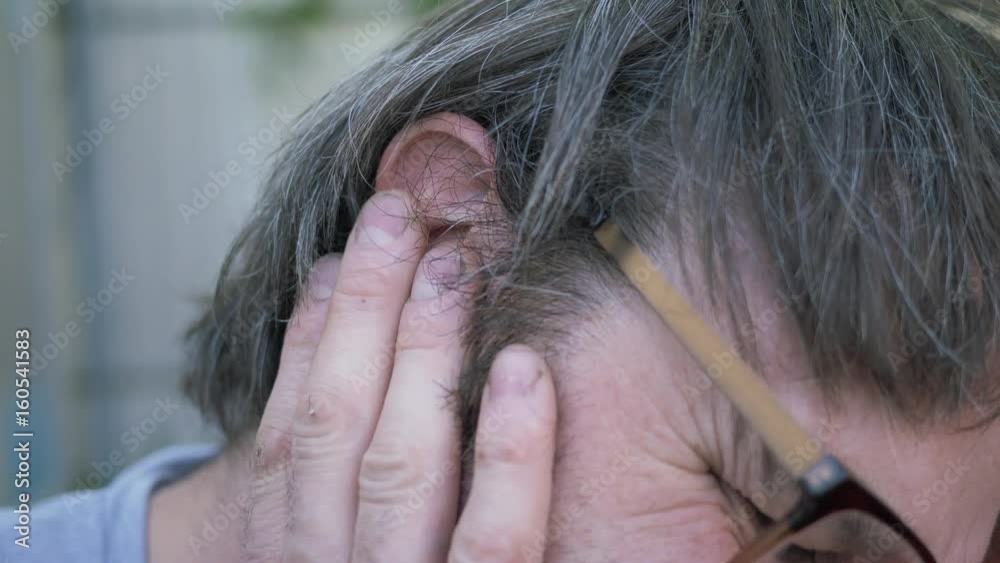 Man in his thirties experiencing some ear pain due to an injury. Filmed outside. Man in his thirties experiencing some ear pain due to an injury. Filmed outside.