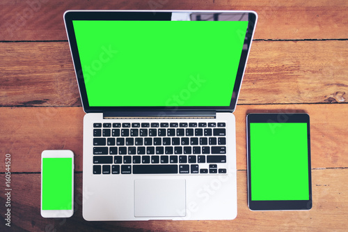 Mockup image of mobile phone , laptop and tablet pc with blank green screen on vintage wood table background