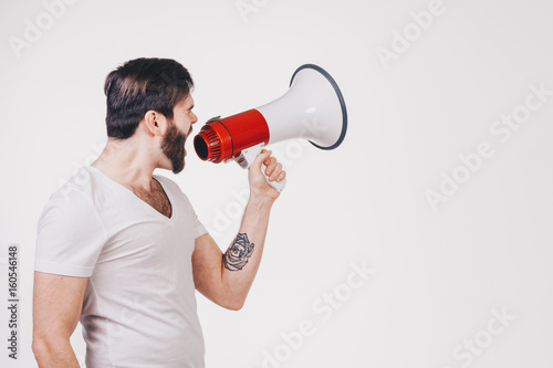 unshaved man in white t-shirt with tattoo call on Loudspeaker
