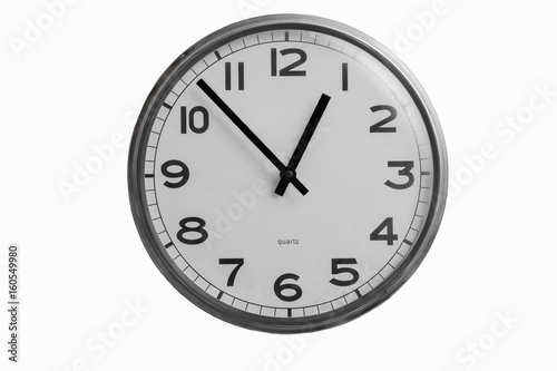 Black and white round wall clock shows almost one o'clock isolated on white background