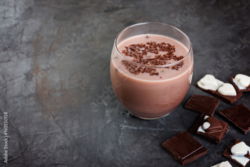 Chocolate smoothie (milkshake) with  banana and chocolate pieces  on a dark  table.