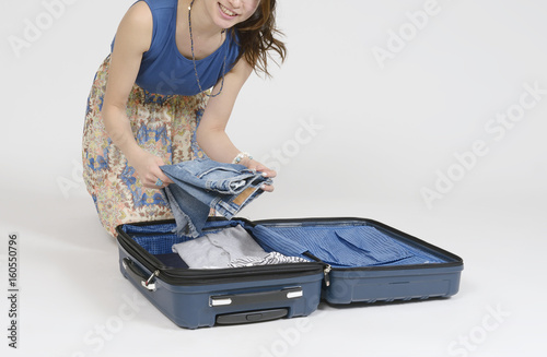 スーツケースに荷物を詰め込む女性