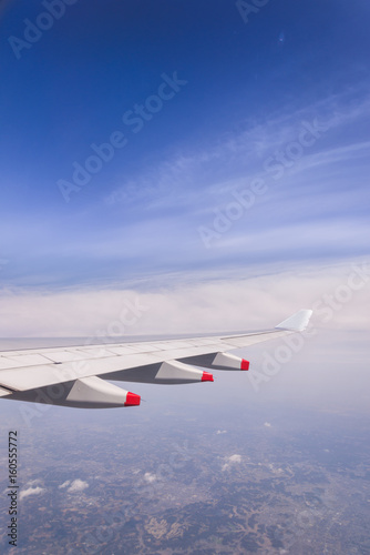 Flying into blue sky and mountain and forest on ground and Wing of airplane with skyline top view as look from window airplane, during flight space for text message, frame or traveling idea concept