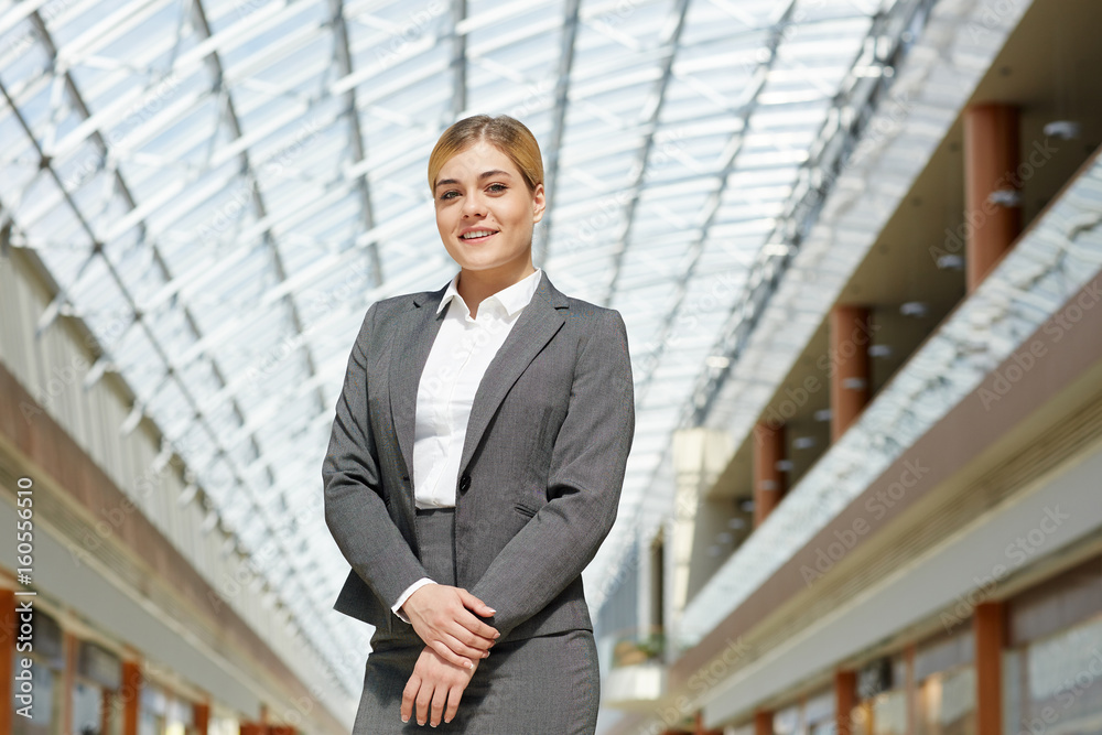 Portrait of confident young businesswoman posing looking at camera in modern office building under glass roof