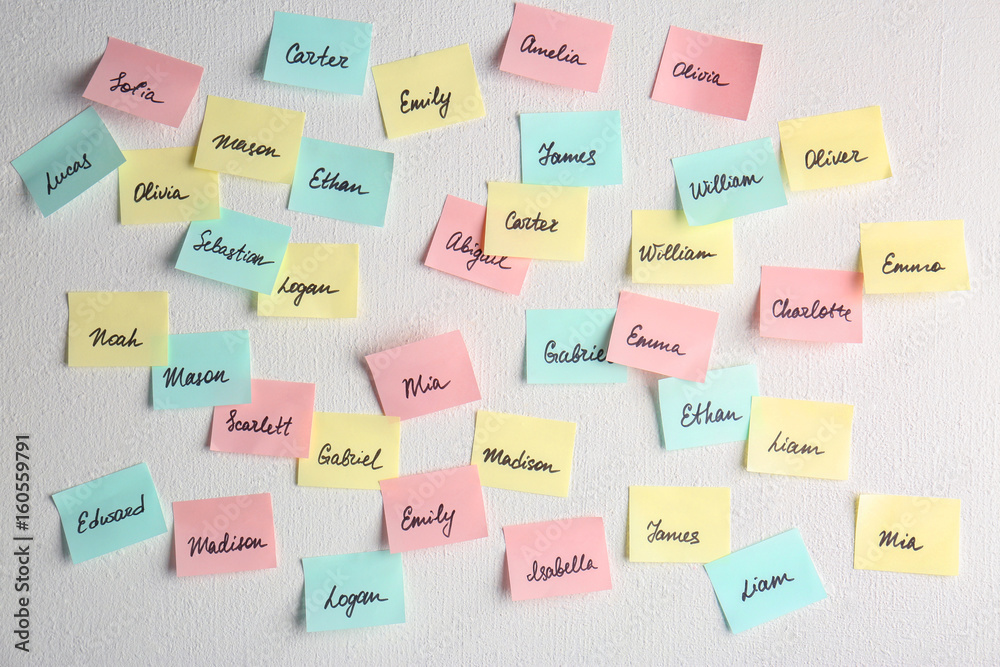 Paper stickers with different names on white wall. Concept of choosing baby name