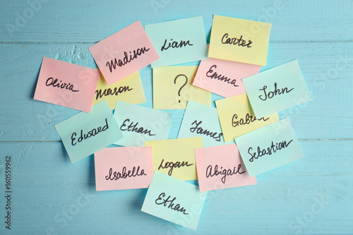 Paper stickers with different names on color wooden background. Concept of choosing baby name