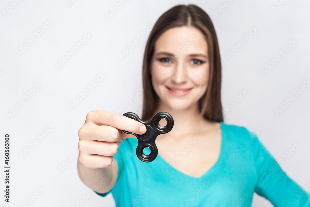 Young beautiful girl holding and playing with fidget spinner. studio shot on white background. Young beautiful girl holding and playing with fidget spinner. studio shot on white background.