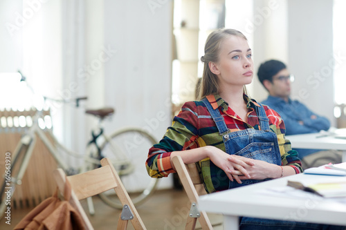 Absent minded girl sitting by desk at lesson © pressmaster