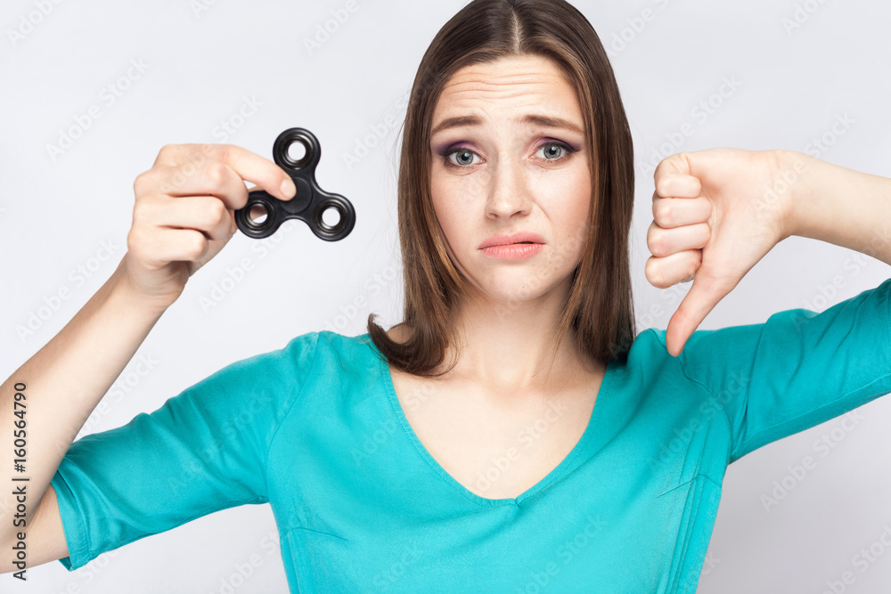 Young beautiful girl holding and playing with fidget spinner. studio shot on white background. Young beautiful girl holding and playing with fidget spinner. studio shot on white background.