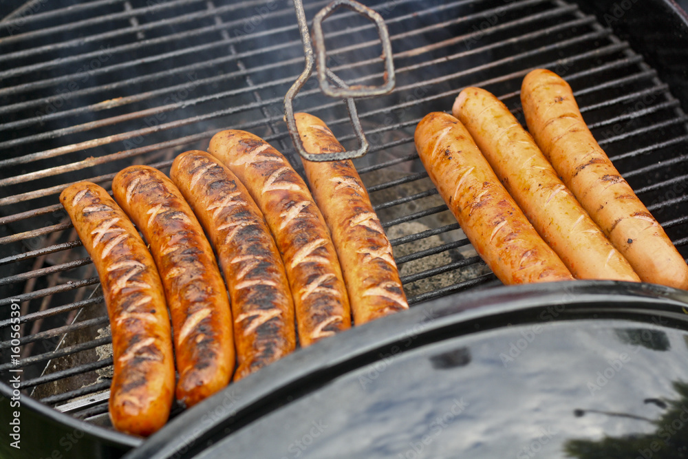 Würstchen auf Grill mit Grillzange, Glut und Rost Stock Photo Adobe Stock