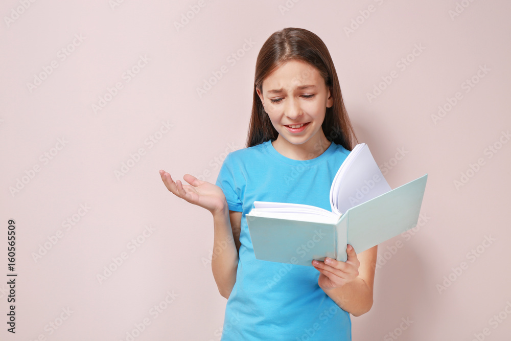 Cute upset girl with book on color background Cute upset girl with book on color background