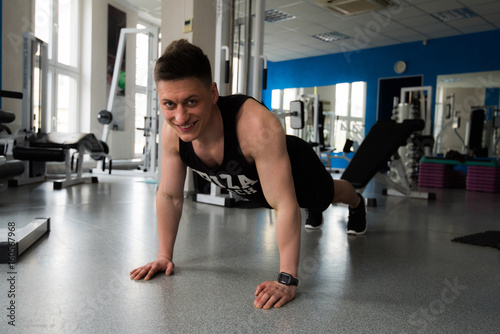 Strong muscular male sportsman working out in gym. A fitness instructor doing exercises. Fitness club gym training lifestyle commercial concept.