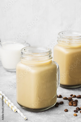 Ice coffee with milk in a tall glass on a gray background