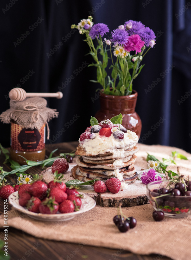 Delicious pancakes with berries and cream on the authentic wooden stand. Summer food still life concept. Delicious pancakes with berries and cream on the authentic wooden stand. Summer food still life concept.