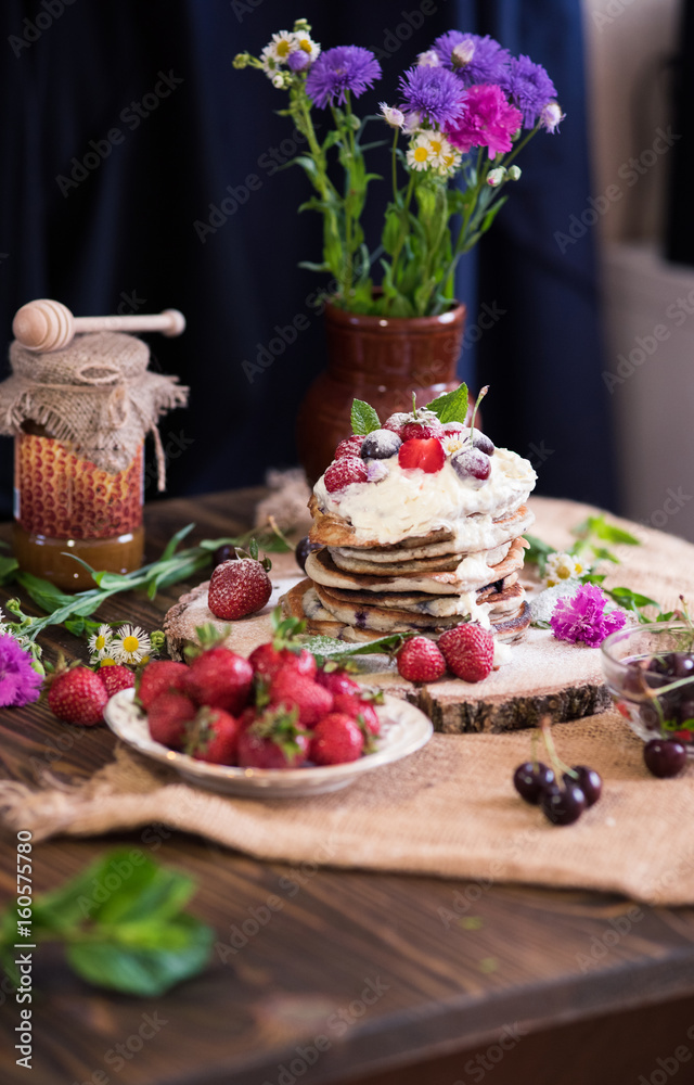 Delicious pancakes with berries and cream on the authentic wooden stand. Summer food still life concept. Delicious pancakes with berries and cream on the authentic wooden stand. Summer food still life concept.