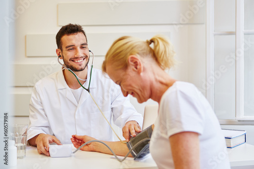 Freundlicher Hausarzt misst Blutdruck © Robert Kneschke