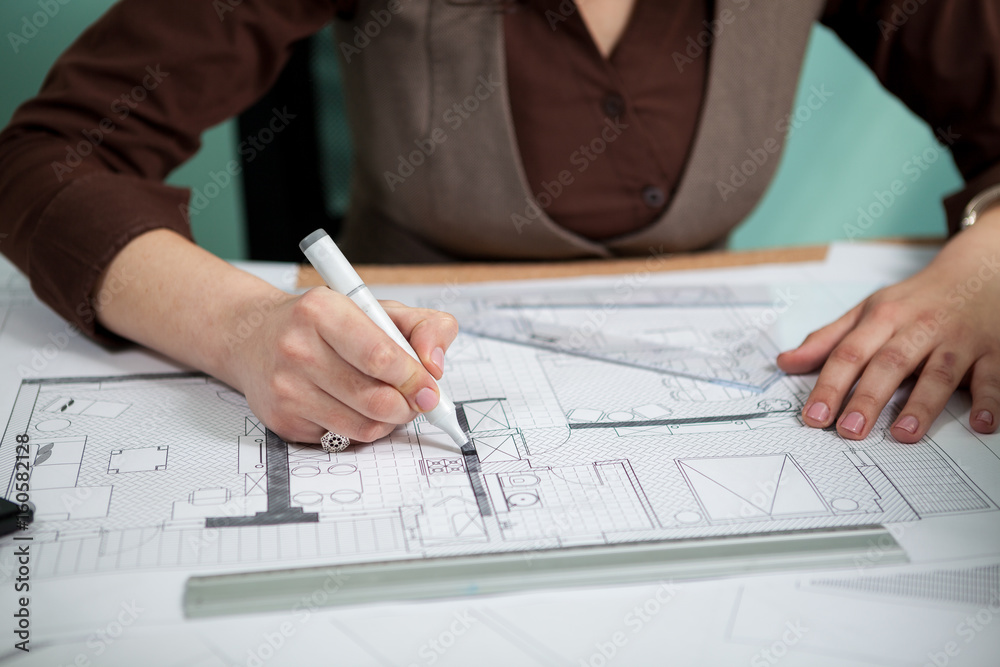 Architect working on blueprints on her desk. Working on new projects. Architecture and design