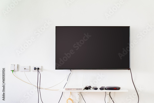 lcd tv on wall with remote, wireless internet access point and set top box photo