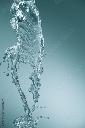 A stream of filtered natural water on a blue background. Splash of mineral drinking water