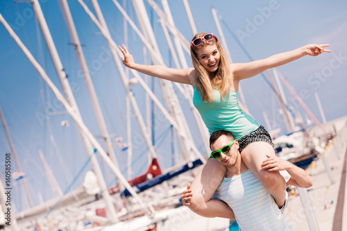 Man giving girlfriend piggyback ride on marina